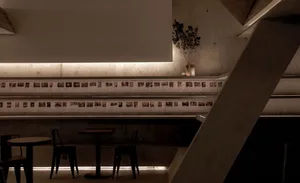 A minimalist cafe with concrete walls and ceiling, featuring several tables and chairs.