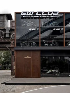 一間工業風格的咖啡酒吧，外牆採用金屬材質，窗外展示著摩托車。