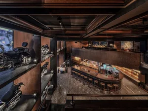 Interior of an industrial-style restaurant bar with metal shelves, wooden decor, and concrete flooring.