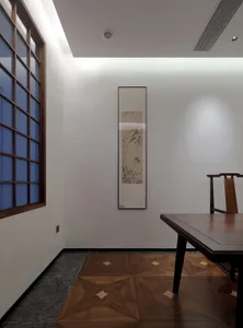 Minimalist office space with a marble floor, featuring a wooden desk, a wooden chair, and a framed artwork on the wall.