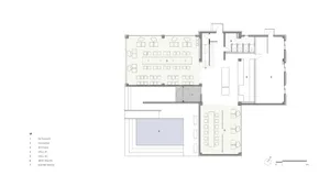 An industrial-style office space with concrete floors, glass partitions, and carpeted areas.
