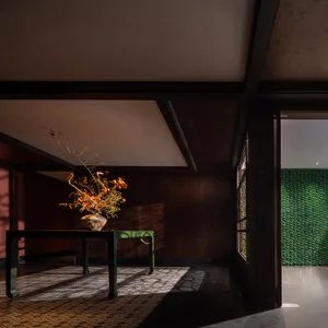 A dark, modern living space featuring wooden paneling and a table with a natural floral arrangement.