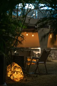 岩石燈在工業風戶外空間中散發溫暖光暈，搭配折疊椅與盆栽植物。