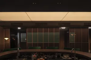 A dimly lit industrial restaurant bar counter with wooden panels and green seating.