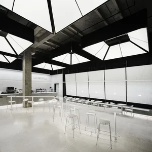 View of a minimalist coffee shop interior with concrete walls and a white ceiling.