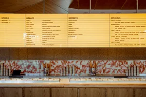 Gelato counter with tiled countertop displaying menu offerings.