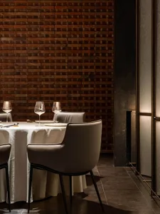 Dining room setting with brick accent wall, white tablecloth, and modern chairs.