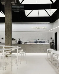 Modern and minimalist coffee shop with white metallic furniture and fixtures.