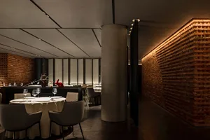 Modern restaurant with brick and concrete interior, featuring round tables, chairs, and minimalist decor.