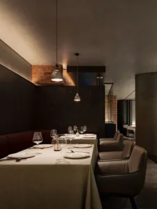 A modern restaurant interior showcasing sleek, concrete finishes with minimalistic design and warm lighting.