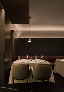A modern restaurant dining table setting featuring a minimalist design with a fabric-covered table and upholstered chairs.
