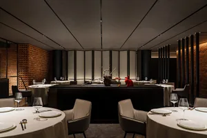 A modern restaurant interior with brick and concrete materials, featuring tables set for dining.