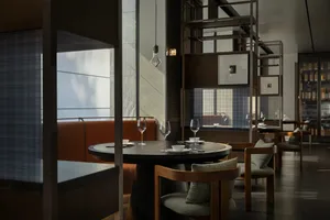 Modern industrial-style restaurant interior with round table, wine glasses, and modern seating.