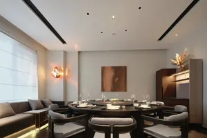 Modern residential dining room featuring a circular wooden table surrounded by upholstered chairs with cushions, a wall-mount