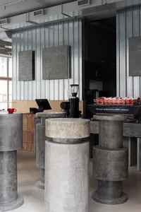 Modern coffee shop with industrial design featuring concrete columns and minimalist decor.