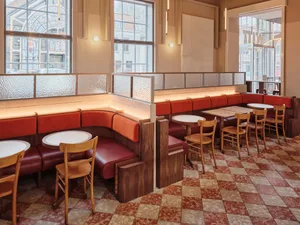 Industrial-style restaurant interior featuring wooden furniture, leather seating, and glass dividers.