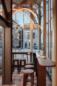 A modern cafe bar with wooden stools and a glass wall.