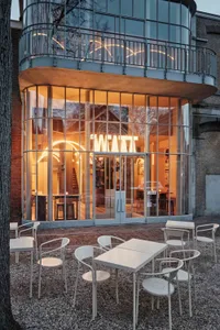 The exterior of a modern cafe with glass walls and a warm, inviting interior.