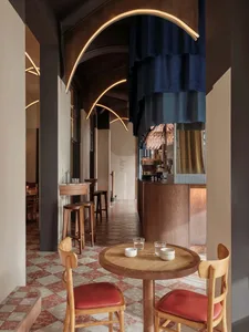 Interior of a modern coffee shop with wooden tables, ceramic mugs, and a metal bar counter.