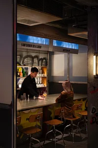 Bar interior with metallic bar top and stools, industrial design aesthetic.
