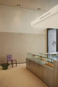 Modern bakery interior with a glass display case filled with pastries and a marble countertop.