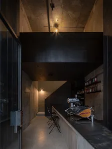 A modern industrial-themed coffee shop with exposed concrete walls and concrete flooring, featuring a sleek espresso machine 