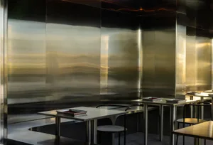 A modern restaurant kitchen with sleek, metallic counters and a minimalist aesthetic.