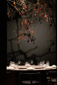 A modern restaurant setting with glass branches adorned with red pomegranates.