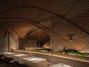 A modern restaurant interior with wooden architectural design and lighting features.