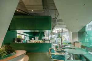 Modern, minimalist cafeteria featuring green metal and glass elements
