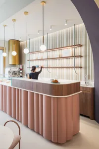 A modern cafe interior with white panels, wooden accents, and pink detailing.