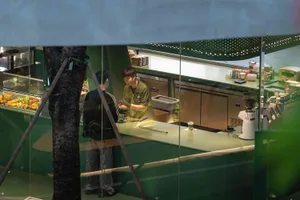 A modern coffee shop interior with a green glass and metal counter.