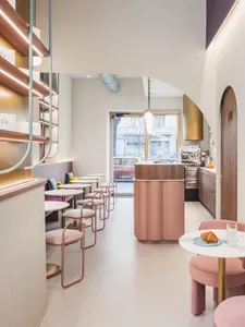 Pastel-colored cafe interior with round tables, chairs, and bar area.