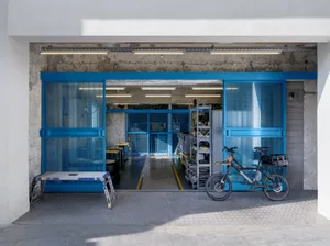 Industrial storage room with blue metal rolling doors, shelves, and a bicycle.