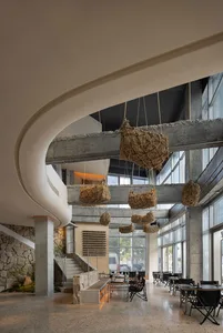 An industrial-style restaurant interior with concrete floors, walls, and hanging baskets.