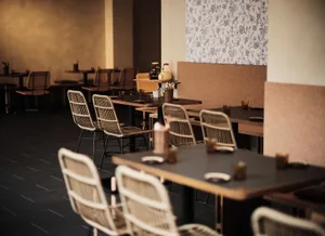 Industrial style restaurant interior with wooden tables and woven fiber chairs