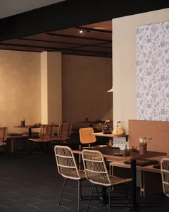 Modern cafe interior with wooden tables, woven chairs, and floral wallpaper