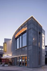 Modern commercial retail storefront with metal netting cladding and illuminated signage