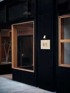 A modern restaurant storefront with black walls, orange accents, and large glass windows.