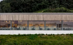 A modern restaurant interior featuring glass walls and a spacious, open design.