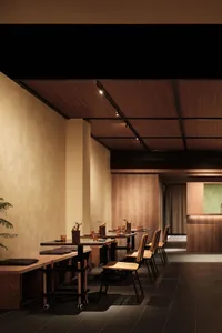 Modern restaurant interior with wooden tables, chairs, and walls, featuring minimalist design.