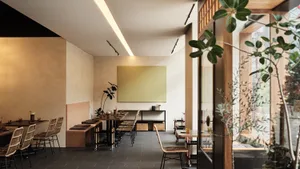 A modern restaurant interior featuring wooden tables, concrete flooring, and green plants