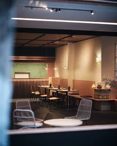 A modern restaurant interior with tables, chairs, and design elements like wood, concrete, and metal.