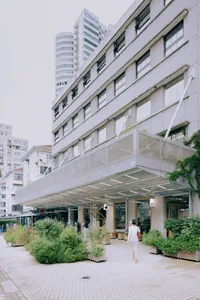 Urban retail storefront featuring concrete exterior, glass display windows, and greenery planters.