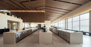 A spacious, industrial-style commercial kitchen with concrete countertops, steel appliances, and large windows.