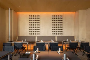 A modern restaurant dining area with wooden walls, metallic elements, and tables.