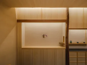 A minimalist kitchen with a wooden interior design, featuring a single small flower arrangement on the countertop.
