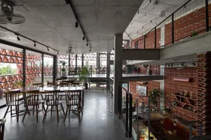 A spacious, industrial-style cafe featuring exposed brick walls and concrete floors.