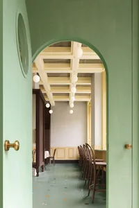 Green and minimalist restaurant interior with wallpaper and modern lighting fixtures.