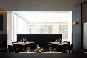 A modern restaurant interior featuring black metal and marble tables, chairs, and accents.